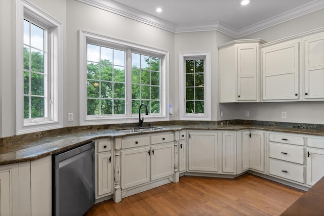 kitchen with dark stone countertops, a sink, crown molding, stainless steel dishwasher, and light wood-style floors
