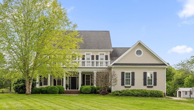 view of front of home featuring a balcony, a front yard, and covered porch