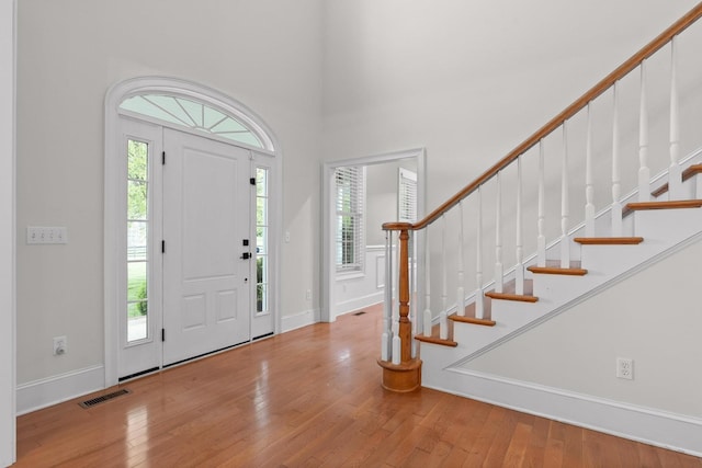 foyer with stairway, hardwood / wood-style flooring, a towering ceiling, and visible vents