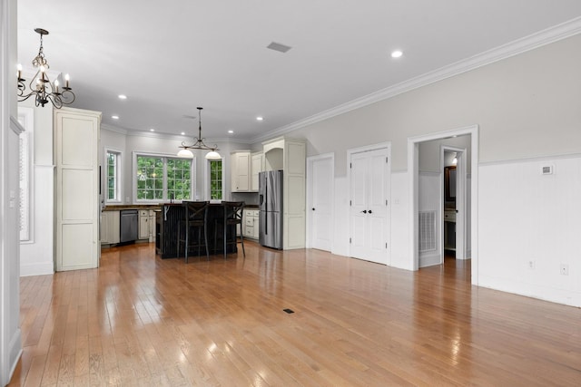 unfurnished living room featuring an inviting chandelier, crown molding, light wood finished floors, and recessed lighting
