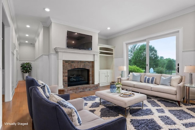 living room with ornamental molding, a fireplace, recessed lighting, and wood finished floors