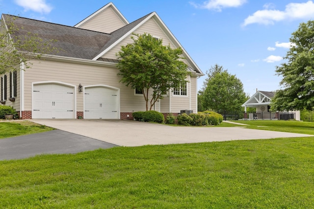 view of front facade with a garage, concrete driveway, a shingled roof, and a front yard