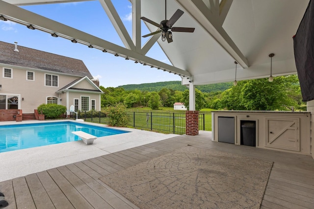 view of swimming pool featuring a ceiling fan, a diving board, a fenced in pool, fence, and a wooden deck