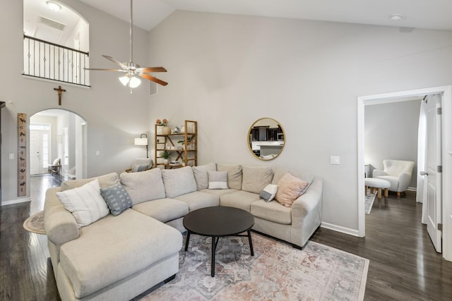 living area featuring ceiling fan, arched walkways, baseboards, and wood finished floors