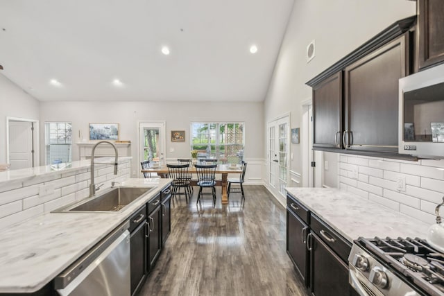 kitchen with a sink, backsplash, light countertops, appliances with stainless steel finishes, and dark wood-style floors