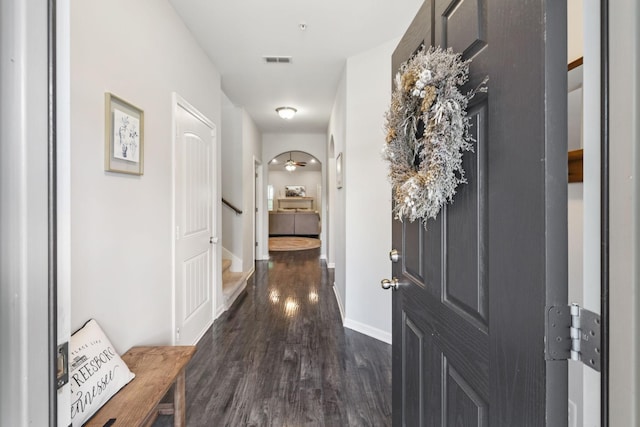 corridor with visible vents, baseboards, stairway, and dark wood-style floors