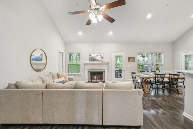 living area with recessed lighting, dark wood finished floors, high vaulted ceiling, and a lit fireplace