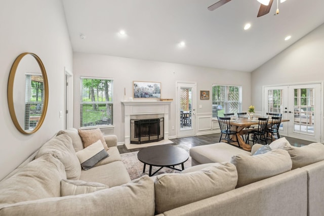 living area with french doors, high vaulted ceiling, recessed lighting, dark wood-style flooring, and a fireplace with flush hearth