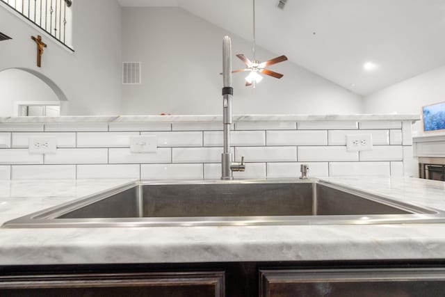 kitchen featuring lofted ceiling, ceiling fan, visible vents, and a sink