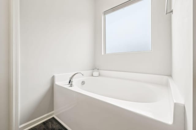 bathroom featuring a garden tub and baseboards
