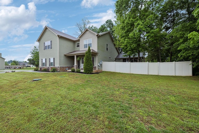 rear view of house with fence and a lawn