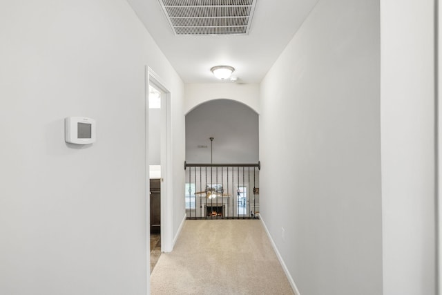 corridor featuring carpet, arched walkways, baseboards, and visible vents