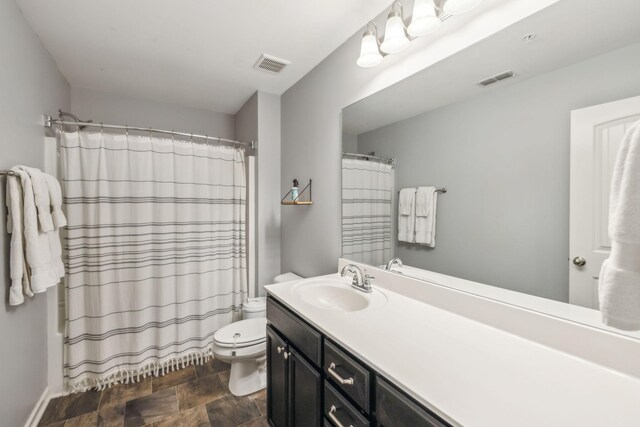 full bathroom featuring toilet, visible vents, vanity, and stone finish flooring