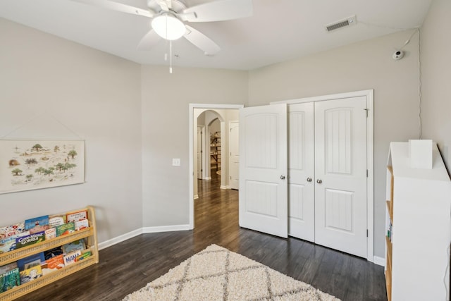 bedroom with a closet, baseboards, dark wood finished floors, visible vents, and arched walkways