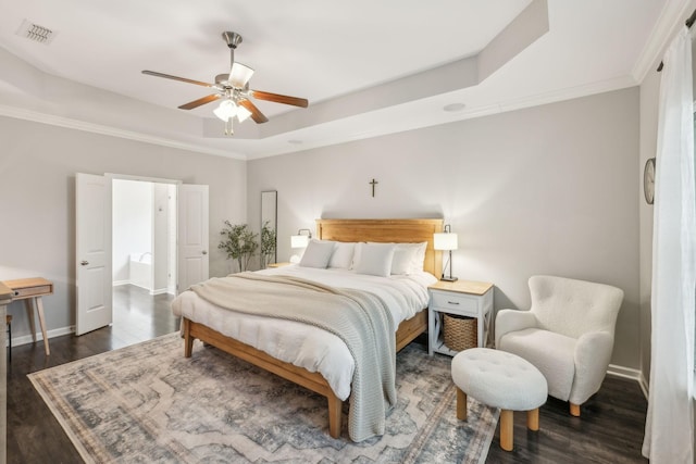 bedroom featuring a ceiling fan, a tray ceiling, baseboards, visible vents, and wood finished floors