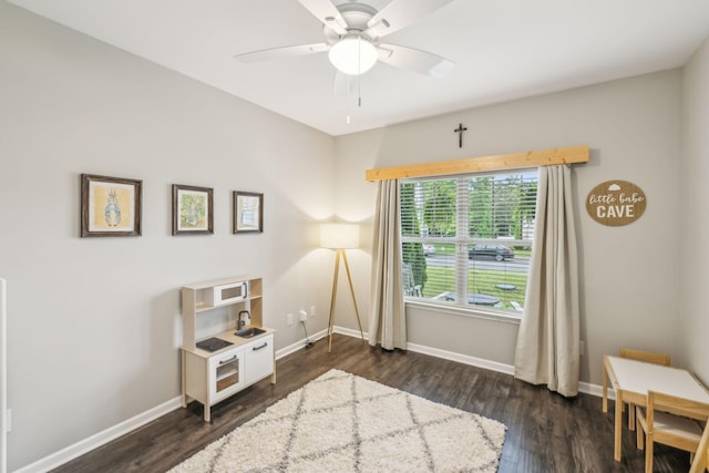 sitting room with baseboards, dark wood-style flooring, and ceiling fan