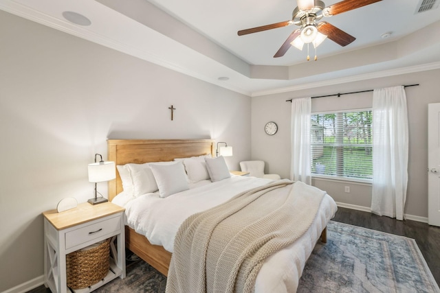 bedroom with a ceiling fan, visible vents, baseboards, a raised ceiling, and dark wood-style floors