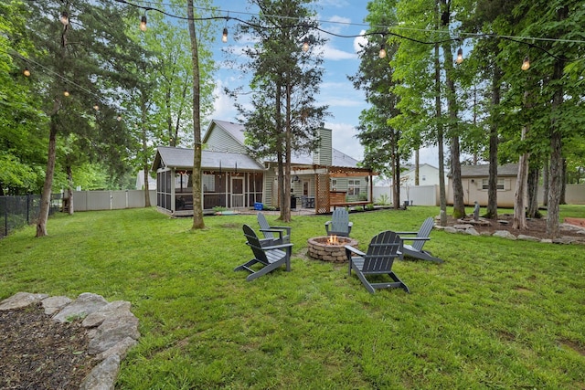 view of yard with an outdoor fire pit, a sunroom, and a fenced backyard