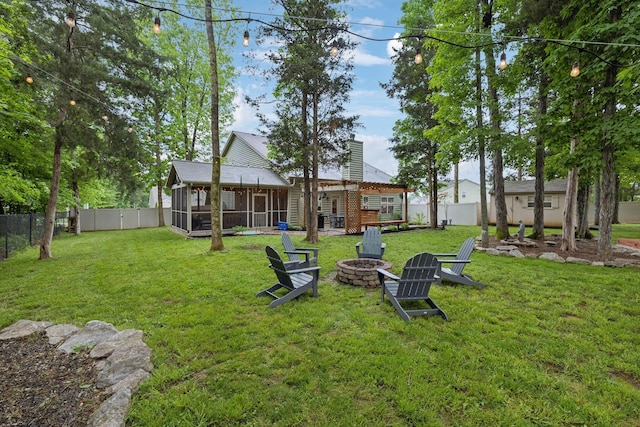 view of yard with an outdoor fire pit, a sunroom, and a fenced backyard