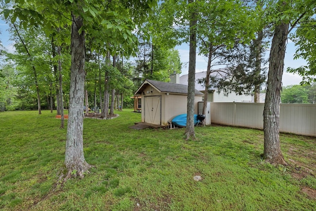 view of yard with a storage unit, fence, and an outbuilding