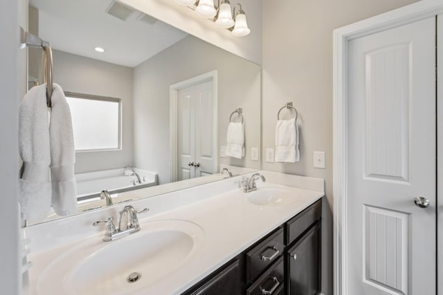 bathroom featuring a sink, double vanity, a bath, and visible vents