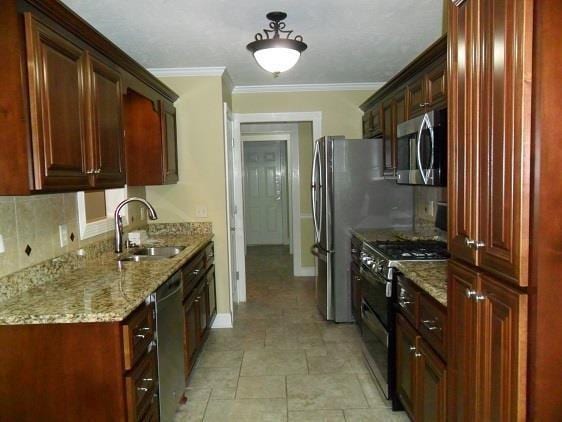 kitchen with a sink, stainless steel appliances, backsplash, light stone countertops, and baseboards
