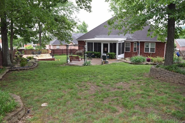 rear view of house with a sunroom, a patio, roof with shingles, a deck, and brick siding