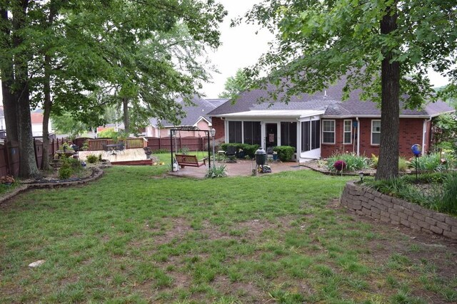 rear view of house featuring a sunroom, a patio, brick siding, and a deck