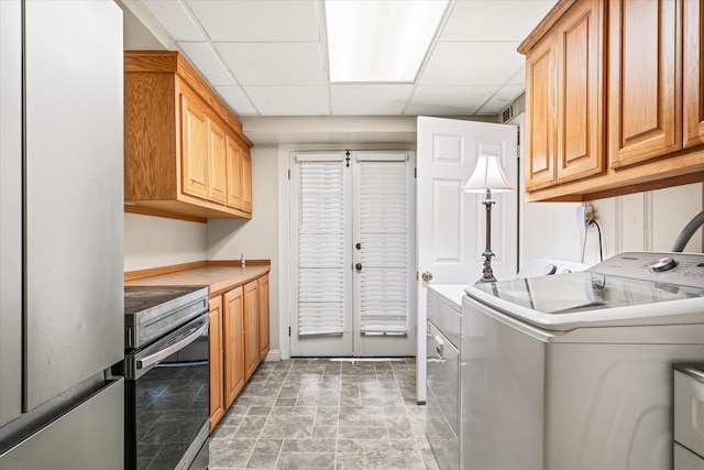 washroom with washing machine and clothes dryer, stone finish floor, and cabinet space