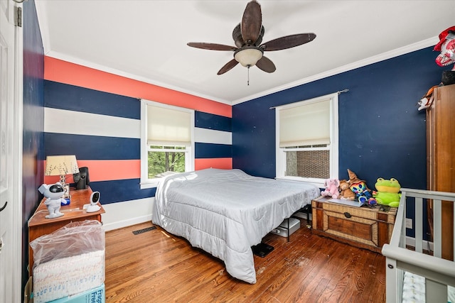 bedroom featuring crown molding, wood-type flooring, baseboards, and ceiling fan
