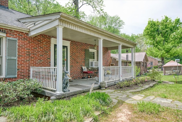 entrance to property featuring covered porch, brick siding, and cooling unit