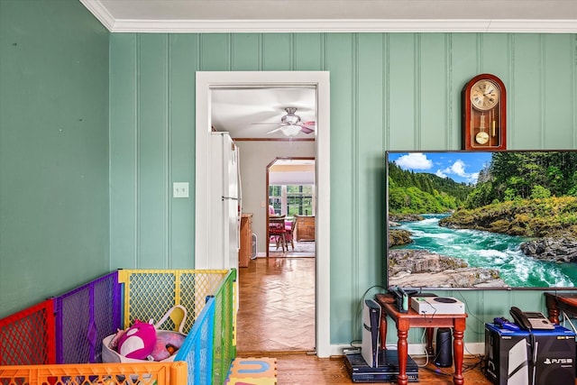 doorway with ceiling fan, ornamental molding, parquet flooring, and a decorative wall