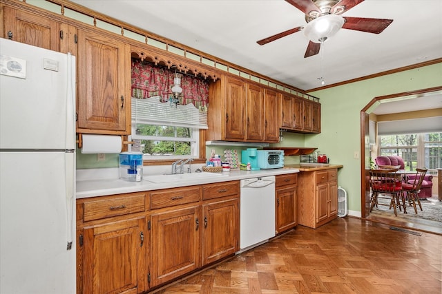 kitchen with light countertops, brown cabinetry, a ceiling fan, and white appliances
