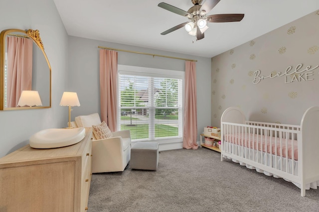 carpeted bedroom featuring a crib and ceiling fan