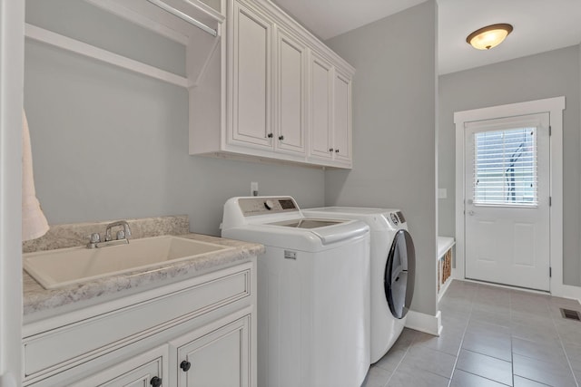 washroom with a sink, cabinet space, visible vents, washer and dryer, and light tile patterned floors