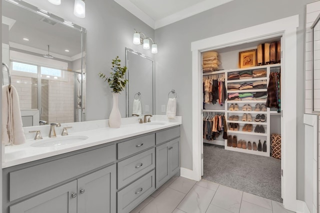 bathroom with double vanity, a stall shower, a sink, a walk in closet, and crown molding