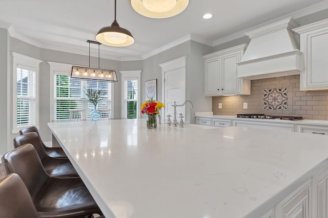 kitchen with white cabinets, gas cooktop, light stone counters, and custom range hood