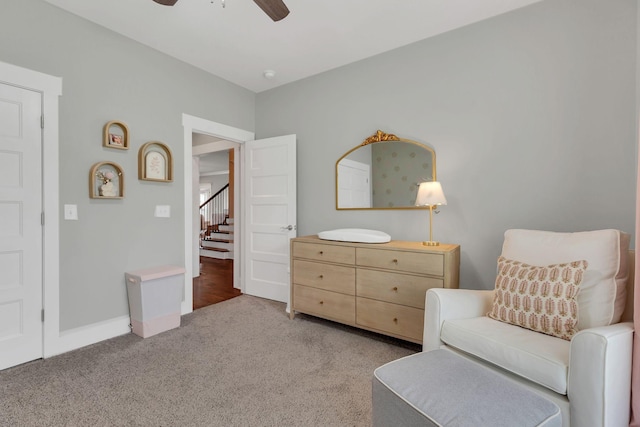 sitting room featuring a ceiling fan, baseboards, carpet, and stairway