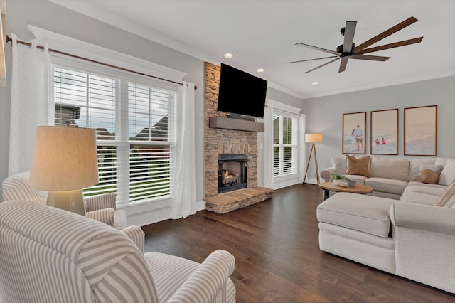 living area with wood finished floors, crown molding, baseboards, a stone fireplace, and ceiling fan