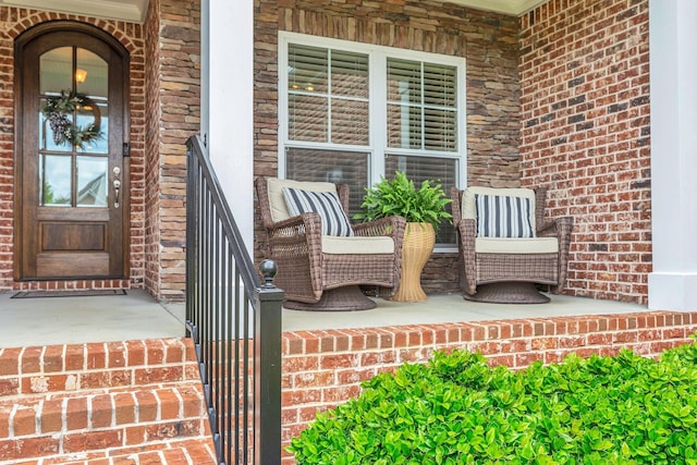 view of exterior entry featuring covered porch and brick siding