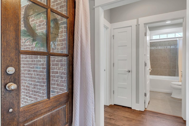 full bath featuring toilet, shower / bath combo with shower curtain, and wood finished floors