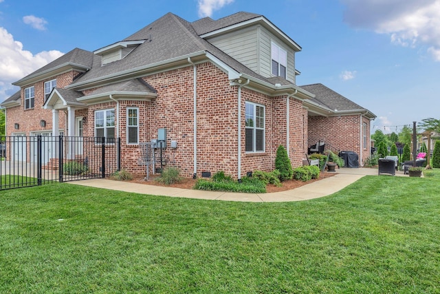 view of side of home with crawl space, fence, a yard, roof with shingles, and brick siding