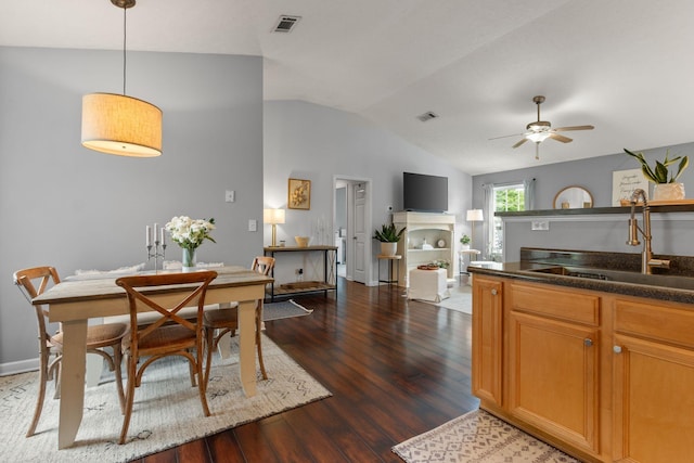dining area featuring a ceiling fan, dark wood-style flooring, visible vents, vaulted ceiling, and a fireplace