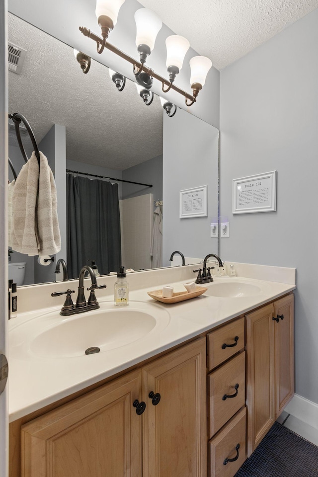 bathroom featuring a textured ceiling, double vanity, and a sink