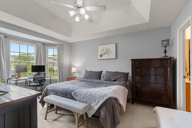 bedroom featuring light carpet, a raised ceiling, and ceiling fan