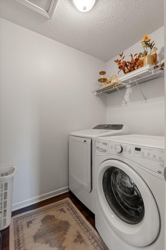laundry area with washer and clothes dryer, laundry area, a textured ceiling, and dark wood-type flooring