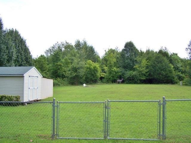 view of yard with a shed, fence, and a gate