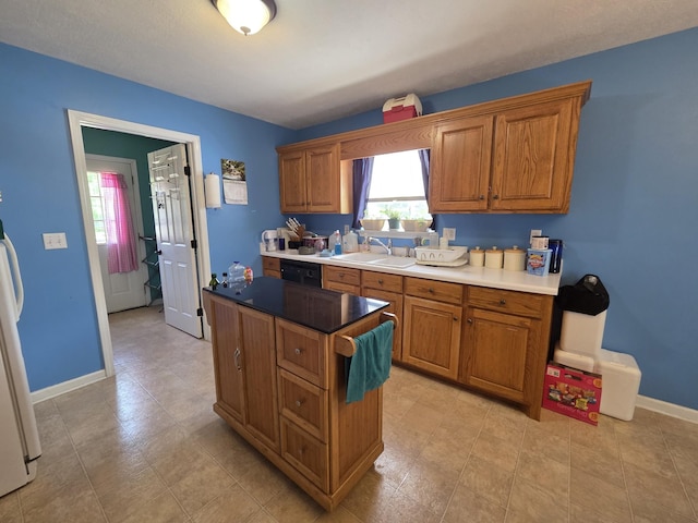 kitchen featuring a sink, brown cabinetry, a kitchen island, and dishwasher