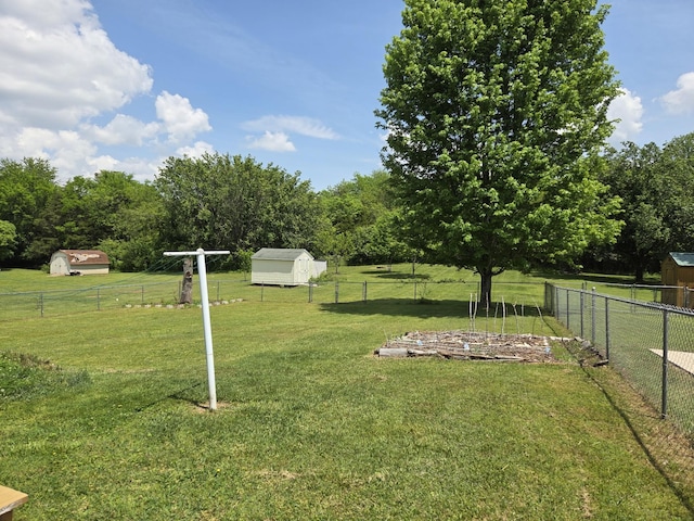view of yard with fence, a shed, and an outbuilding