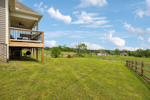view of yard with fence, a deck, and a ceiling fan